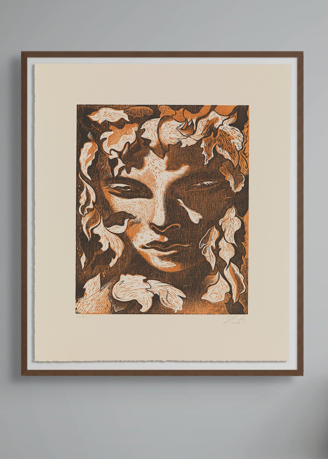 Framed artwork by Dennis Scholl of a face with floral elements on a gray wall.