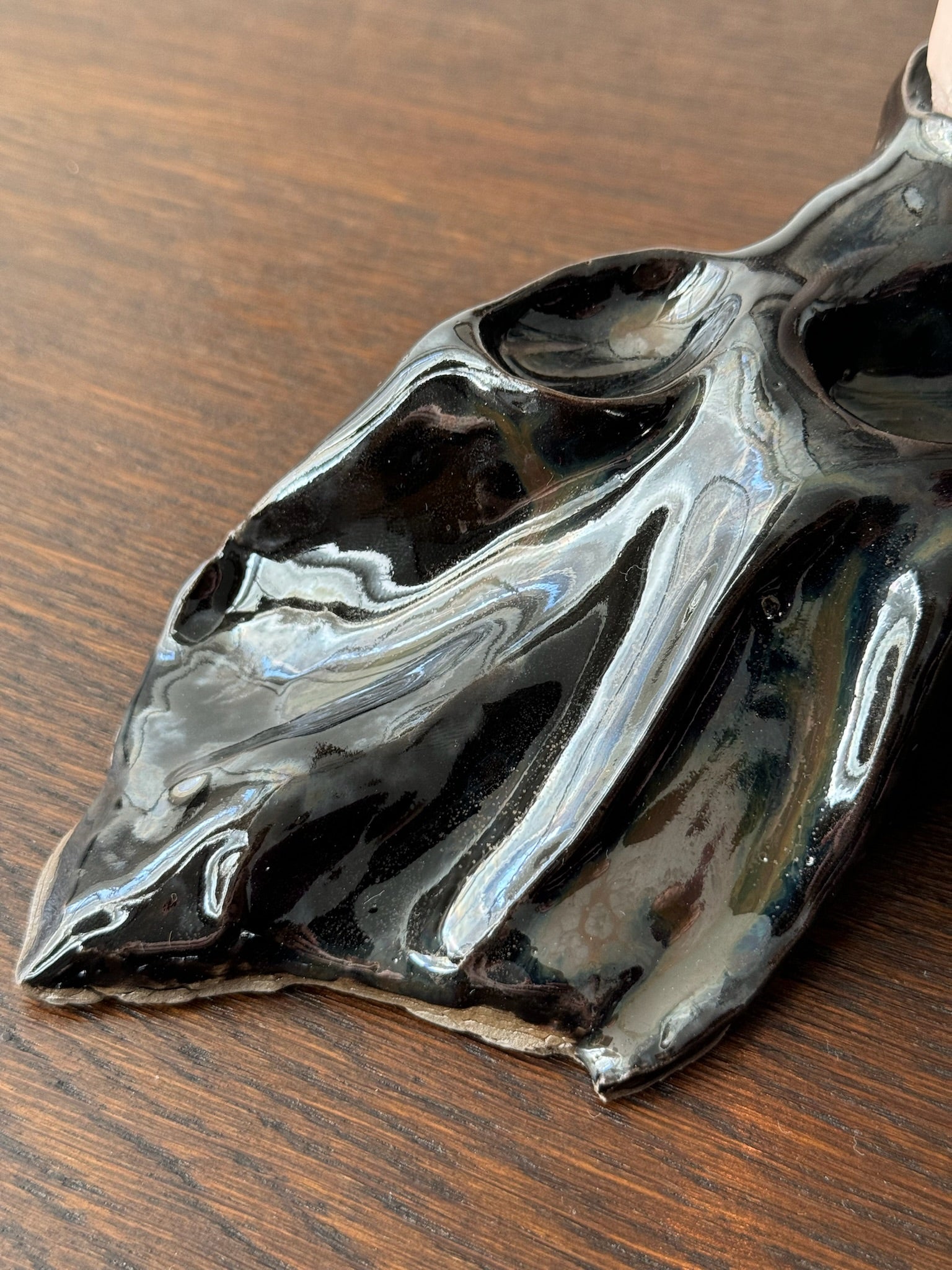 Detail of a black candleholder with a shimmering glaze by Aline Schwörer