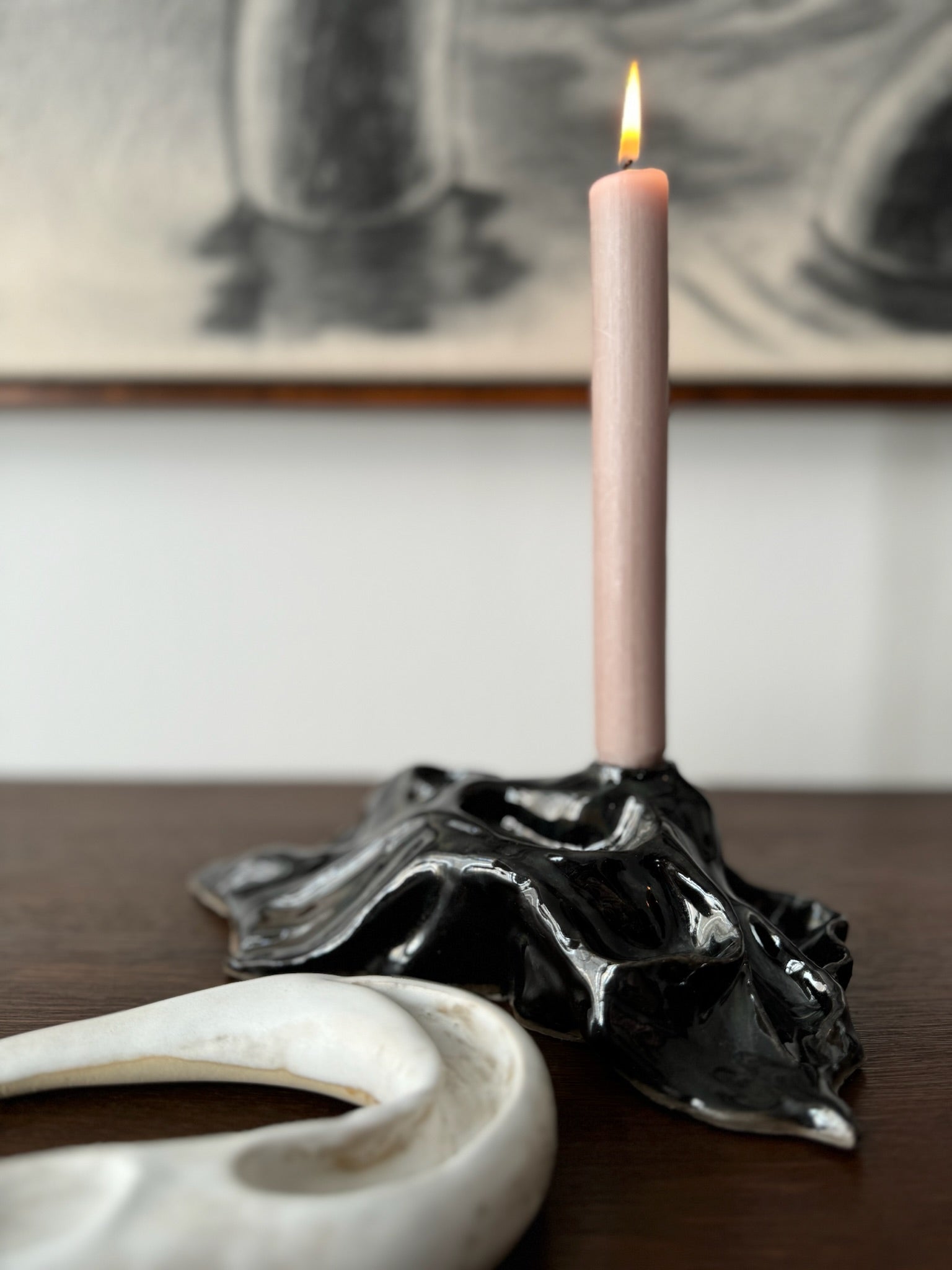 Black candleholder with candle and detail of white ceramic by Aline Schwörer