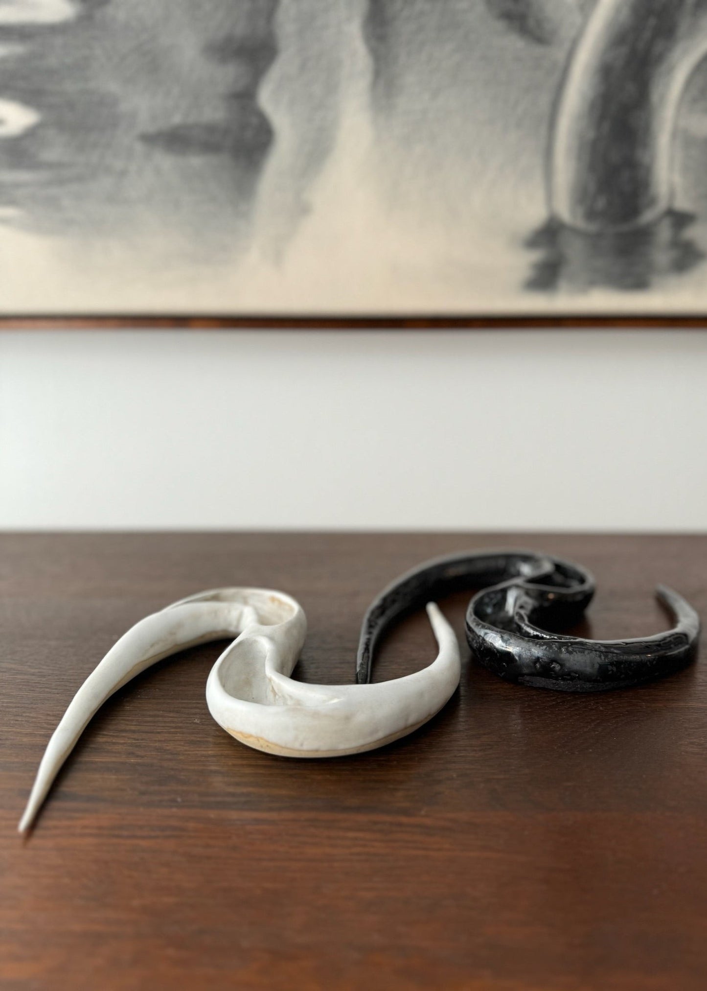 Two ceramic artworks by Aline Schwörer resembling the form of a snake in black and white.