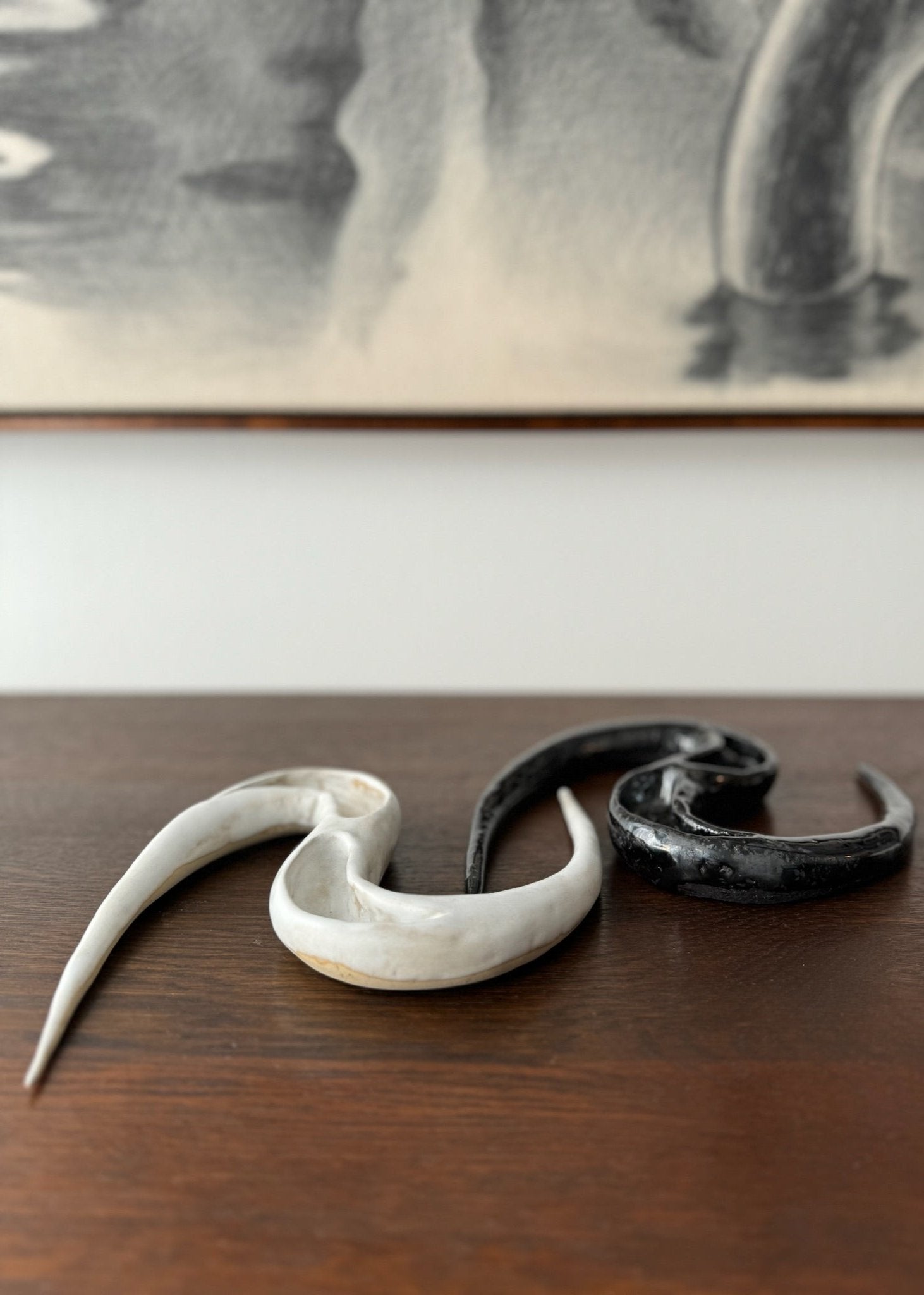 Two ceramic artworks by Aline Schwörer resembling the form of a snake in black and white.