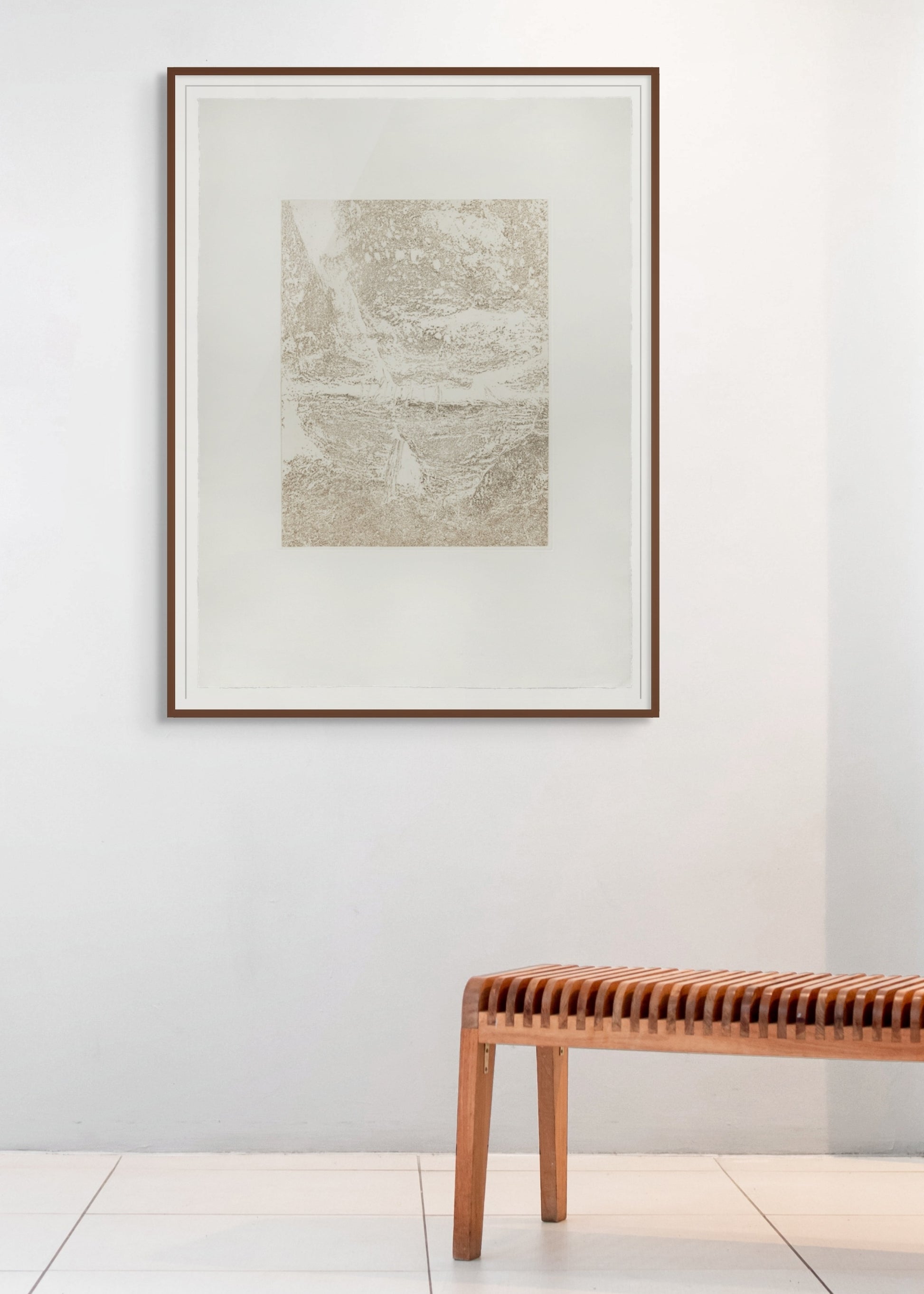 Framed abstract art on a white wall with a wooden bench below.