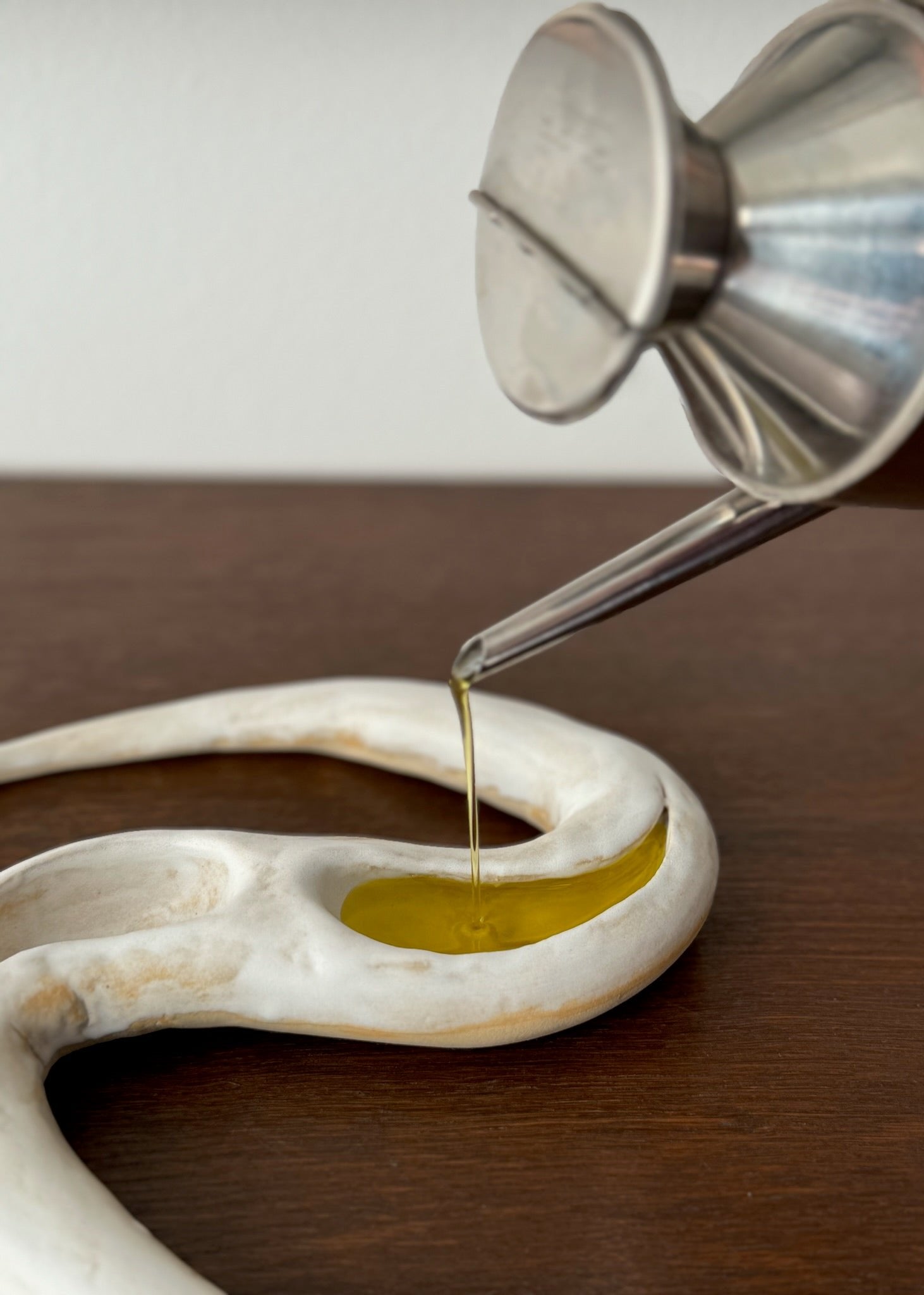 Oil being poured into a white ceramic by Aline Schwörer