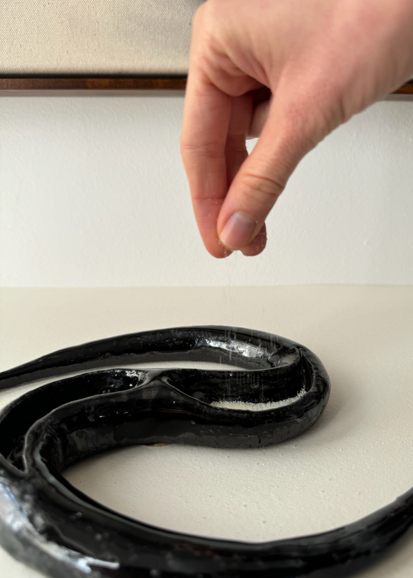 Salt being drizzled into a black ceramic by Aline Schwörer