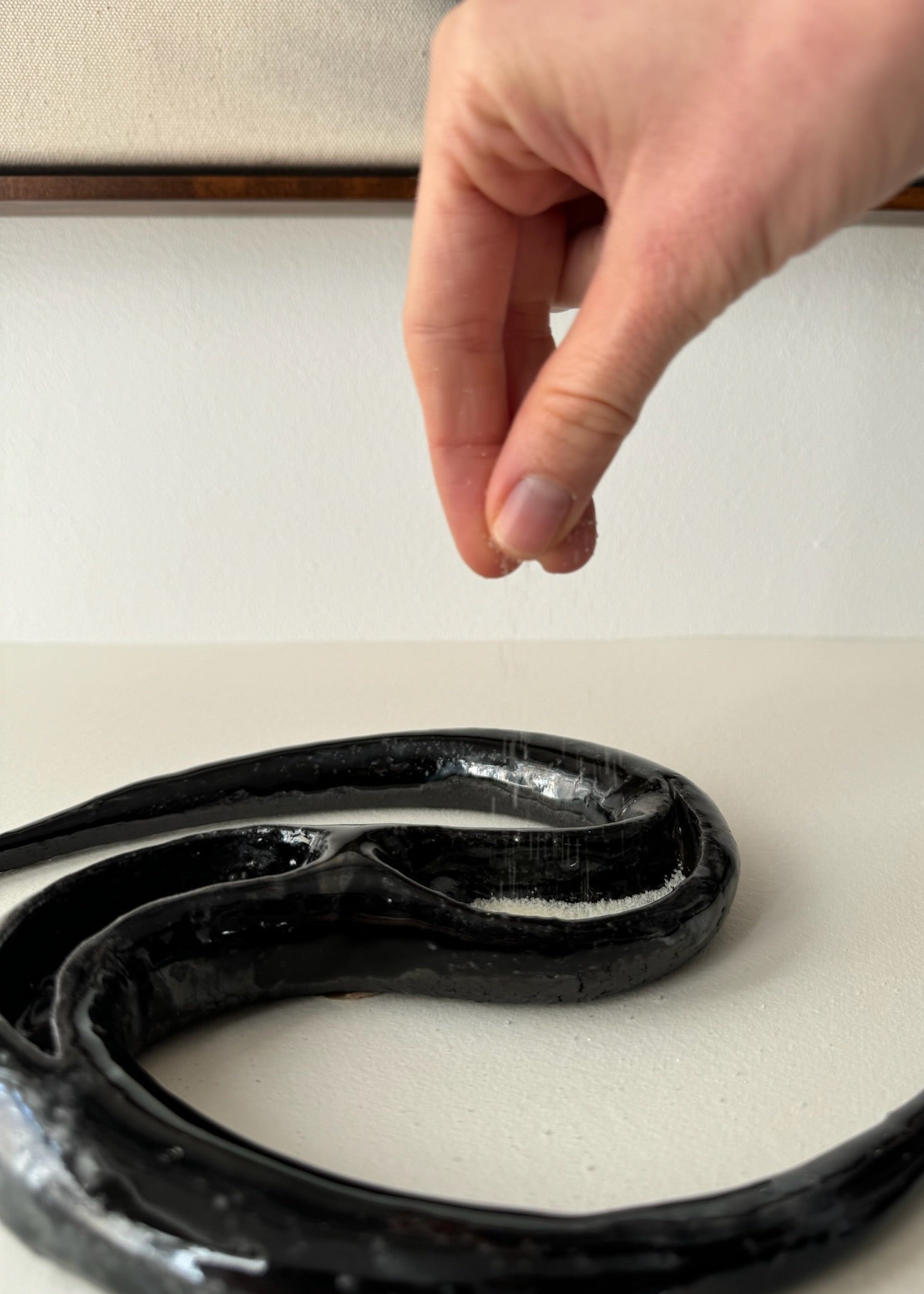 Salt being drizzled into a black ceramic by Aline Schwörer
