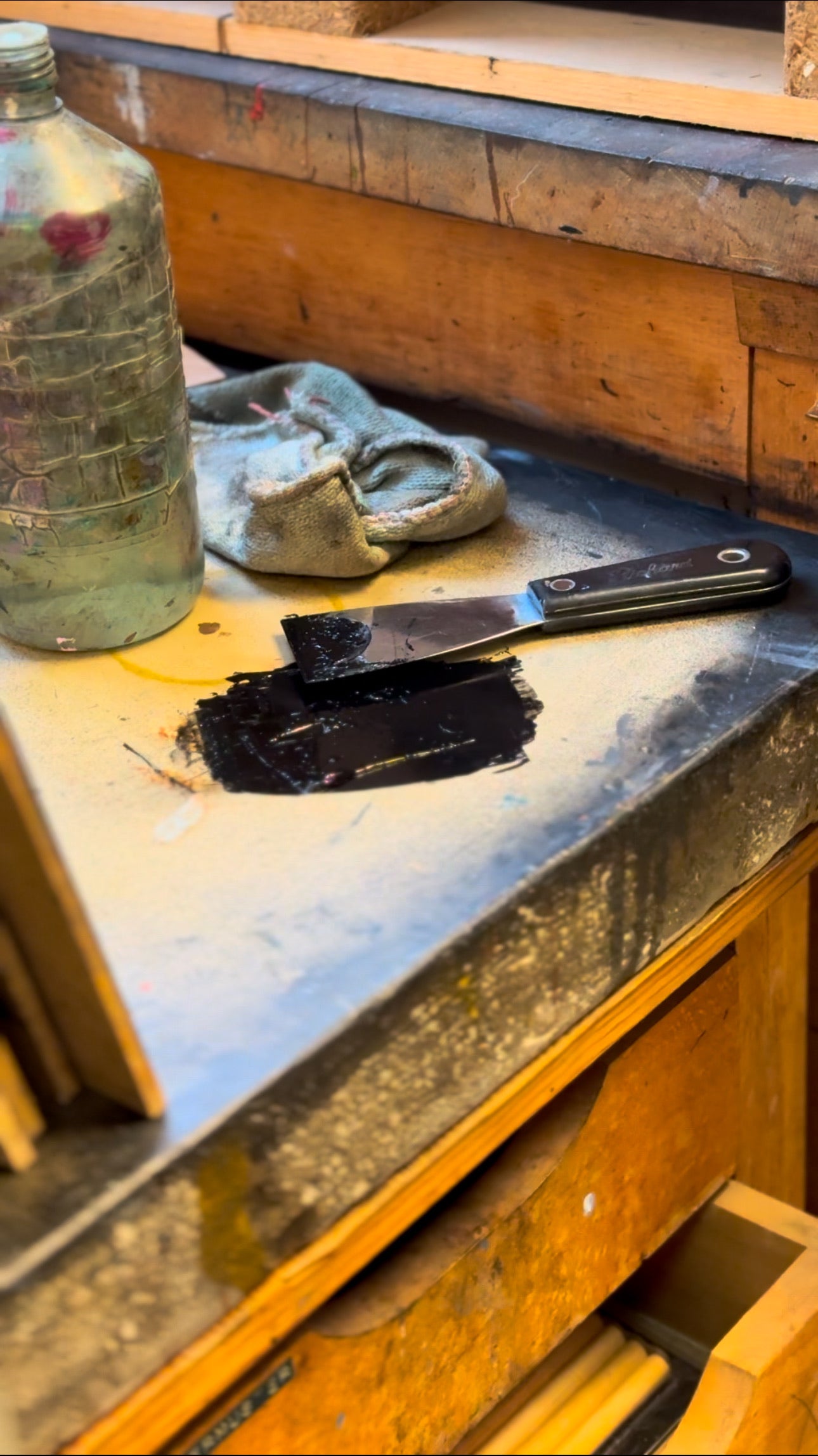 Workbench with a bottle, gloves, and tools on a wooden surface