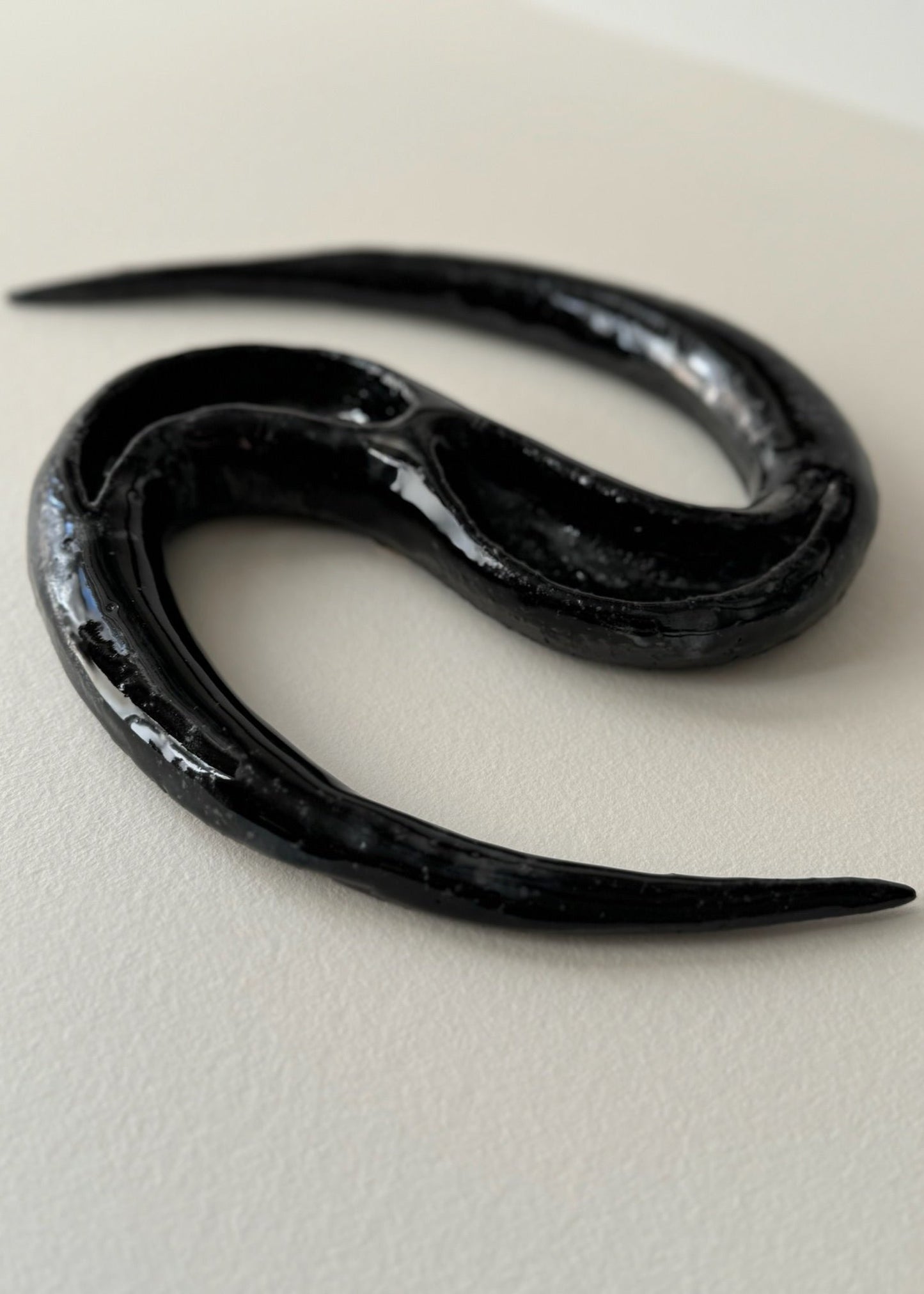 Black ceramic artwork resembling a snake by Aline Schwörer
