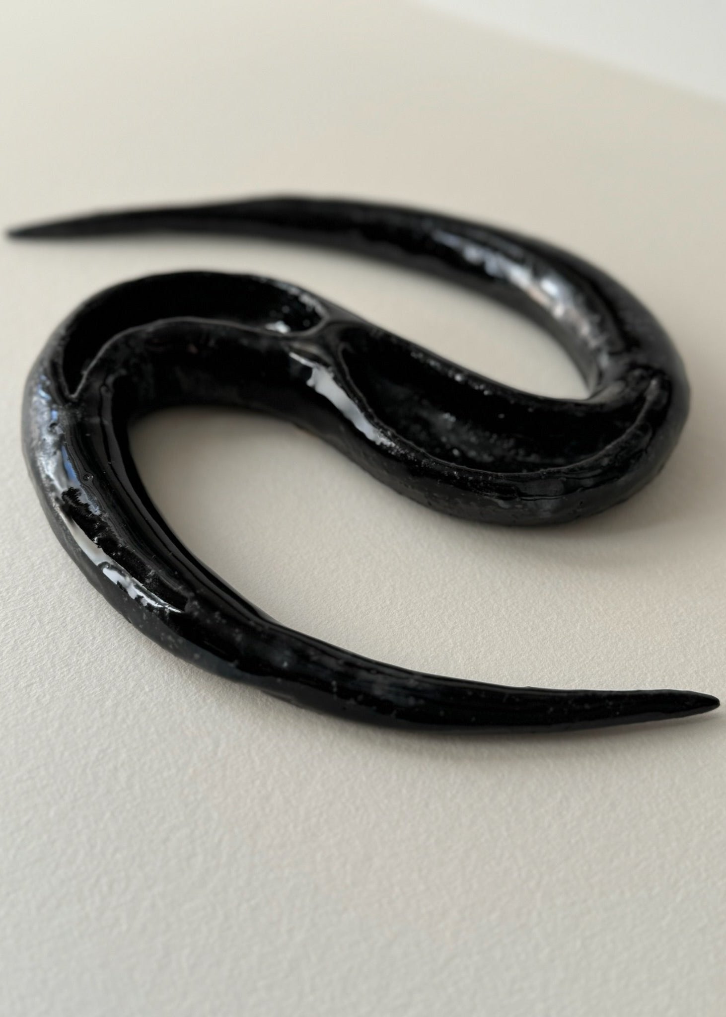 Black ceramic artwork resembling a snake by Aline Schwörer