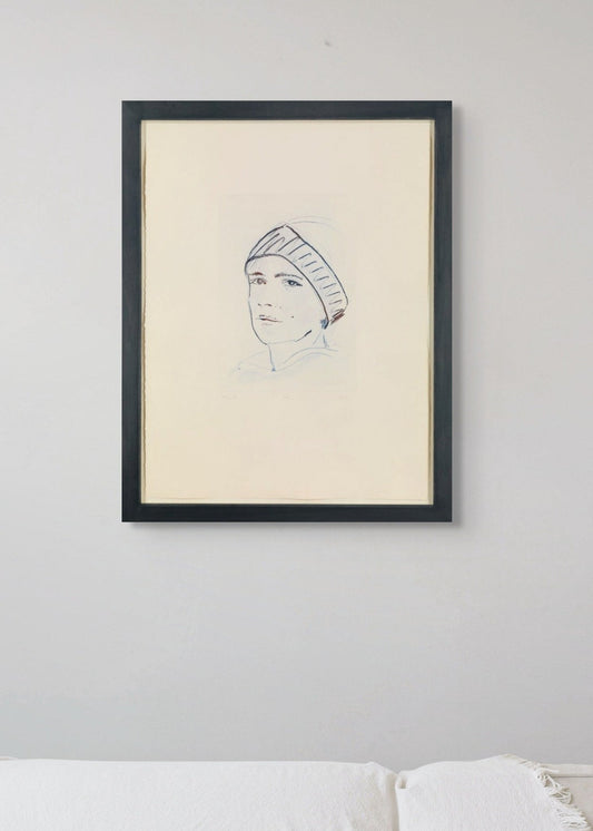 Framed portrait above a white sofa on a light gray wall