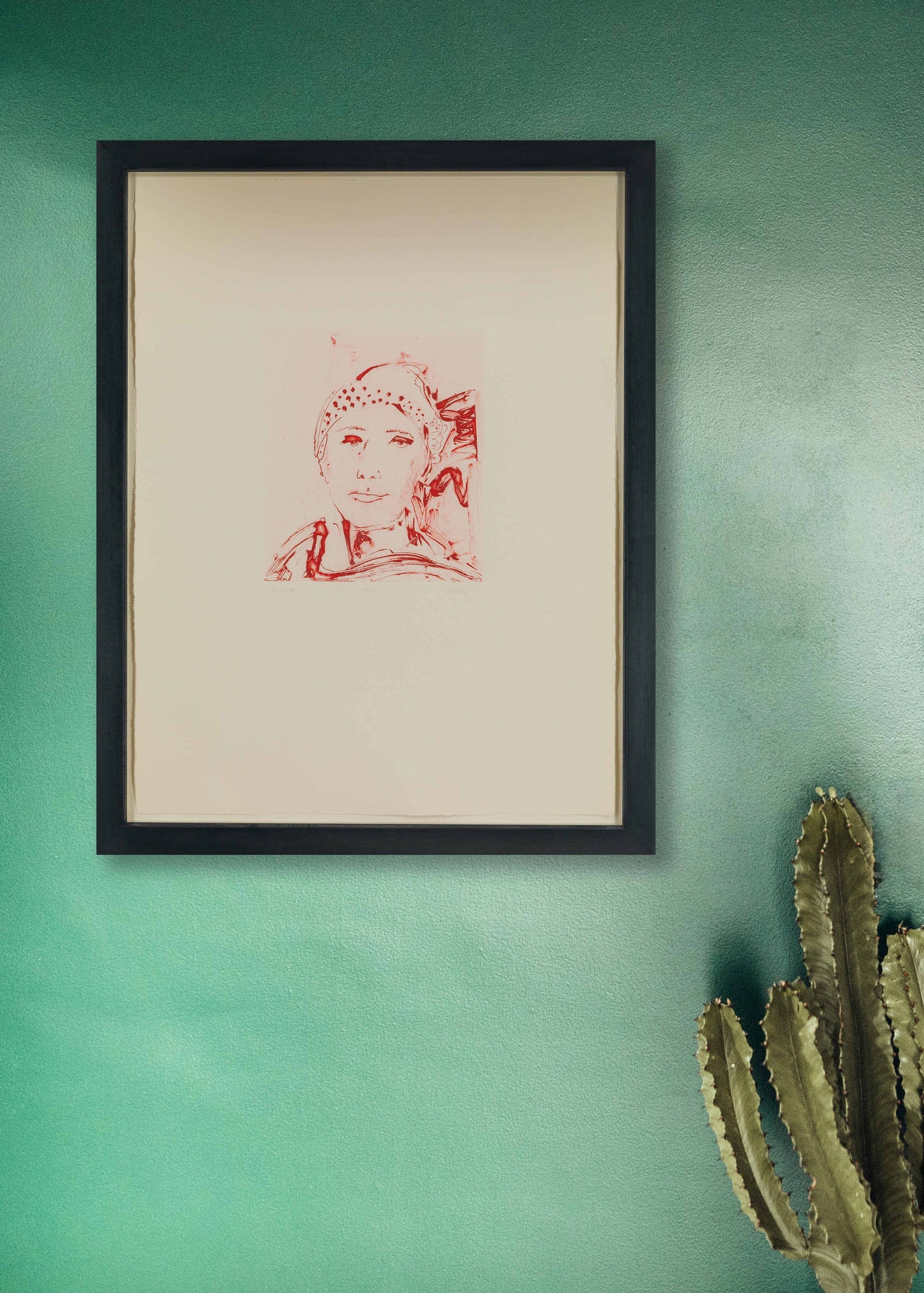 Framed artwork by Thomas Schütte on a green wall with a cactus plant.