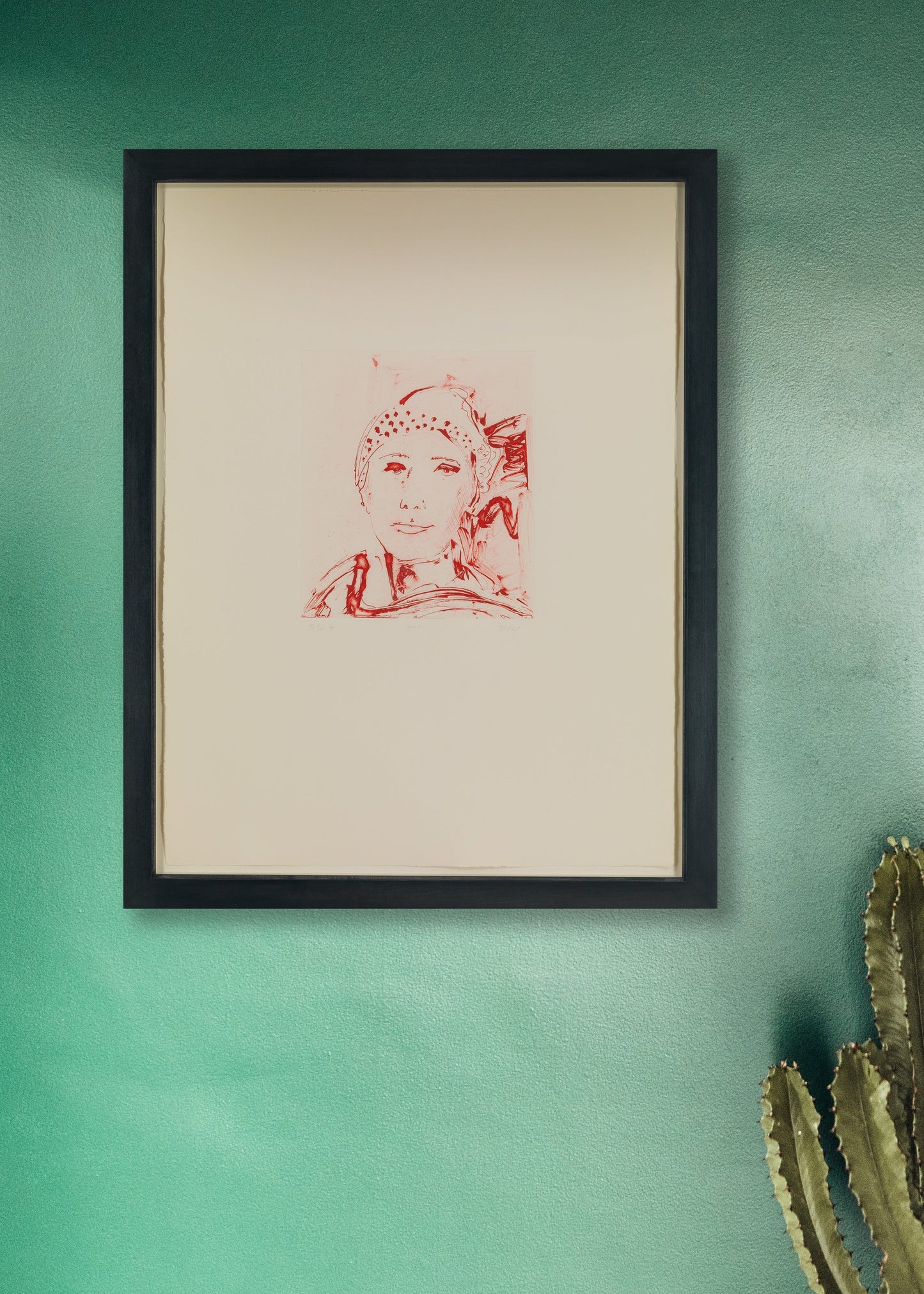 Framed artwork by Thomas Schütte on a green wall with a cactus plant.