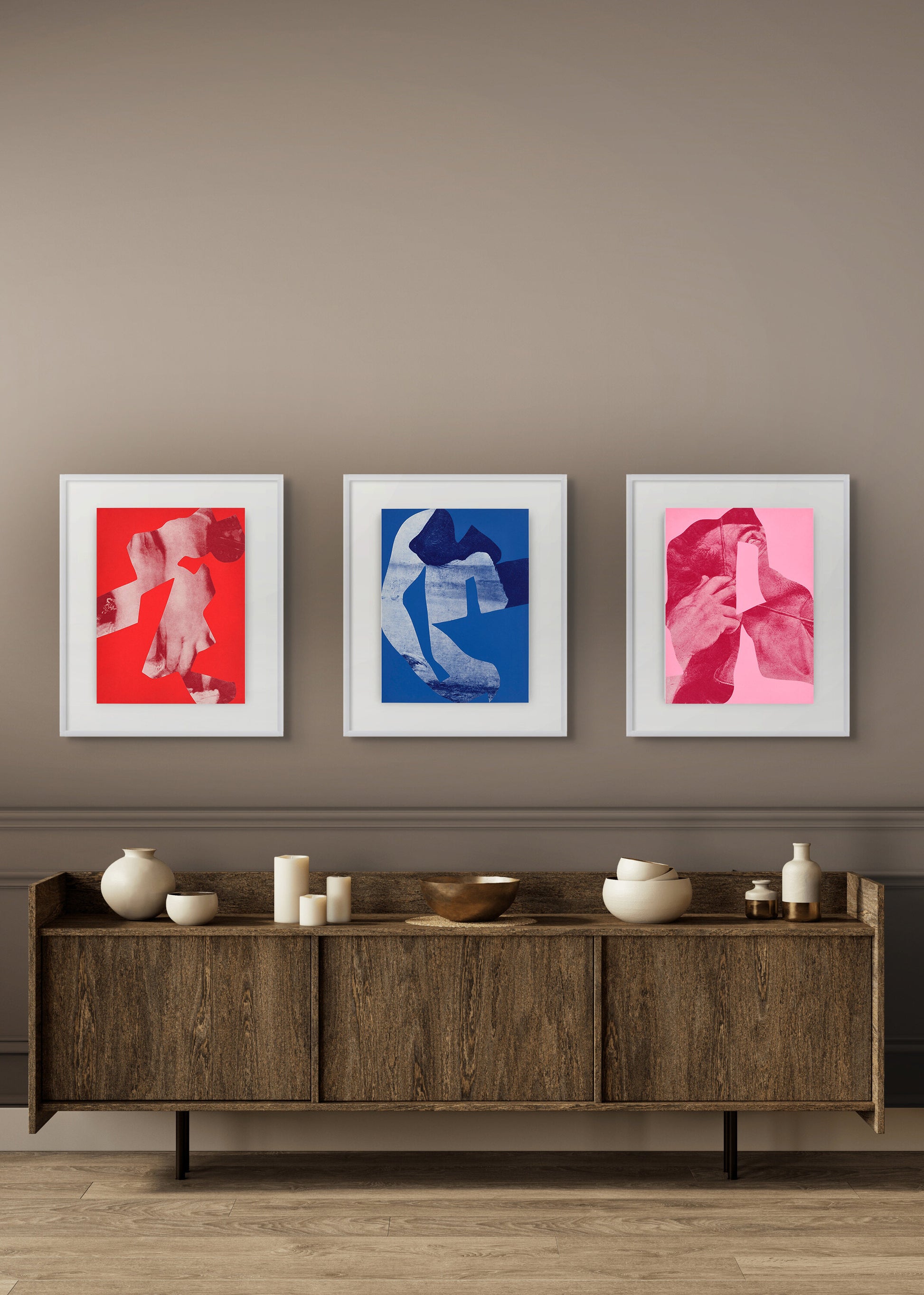 Three framed artworks on a wall above a wooden sideboard with decorative items.