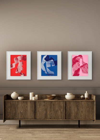 Three framed artworks on a wall above a wooden sideboard with decorative items.