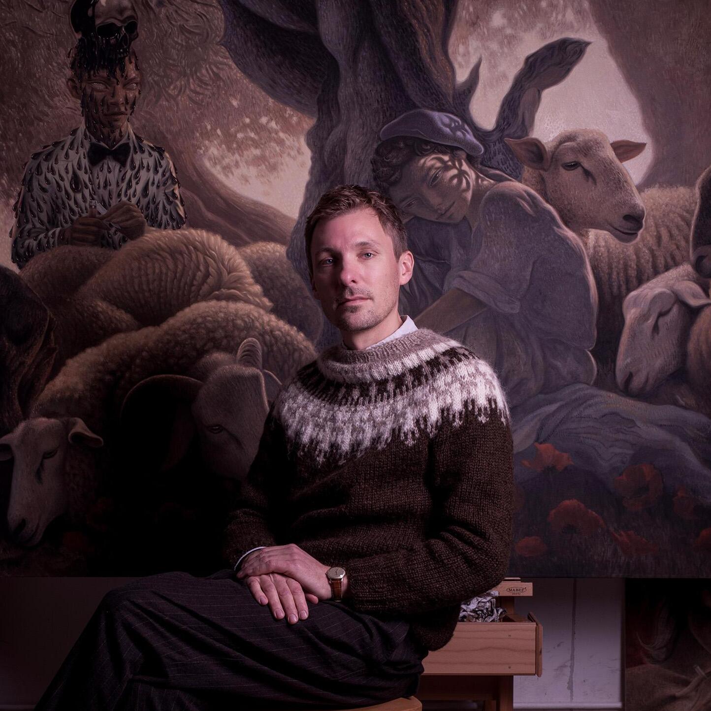Portrait of Dennis scholl in front of one of his paintings with sheep and figures. 