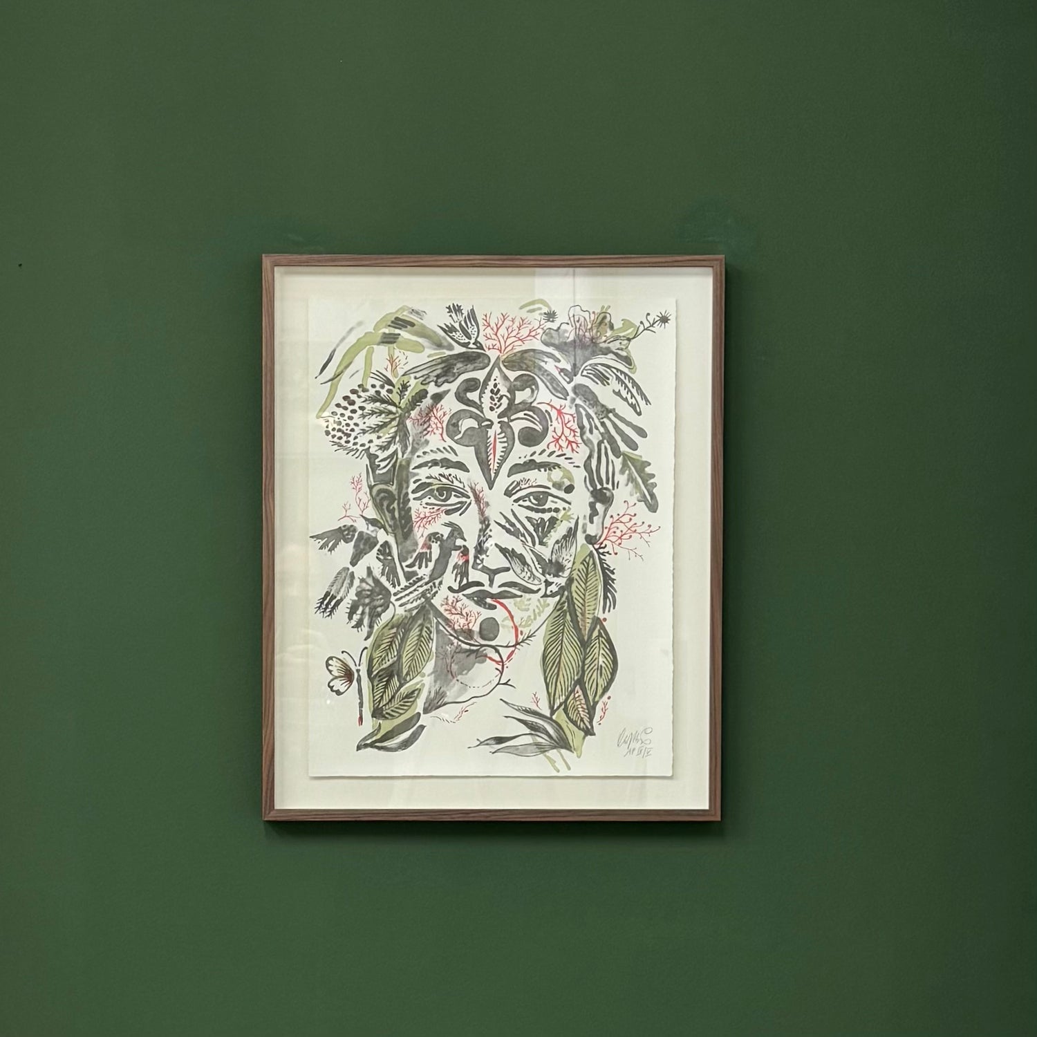 Framed artwork of a face with floral elements by Olaf Hajek on a green wall