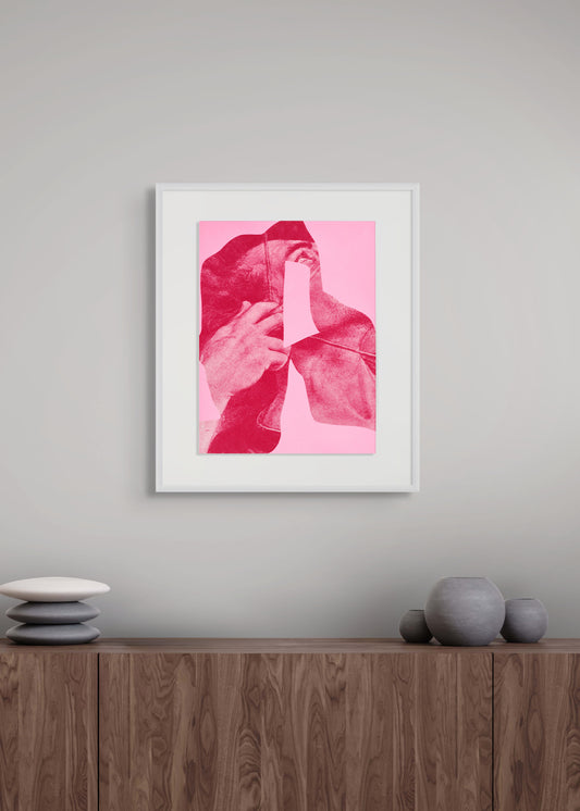 Framed artwork by Arturo Herrera with a pink and red abstract design on a gray wall above a wooden cabinet.