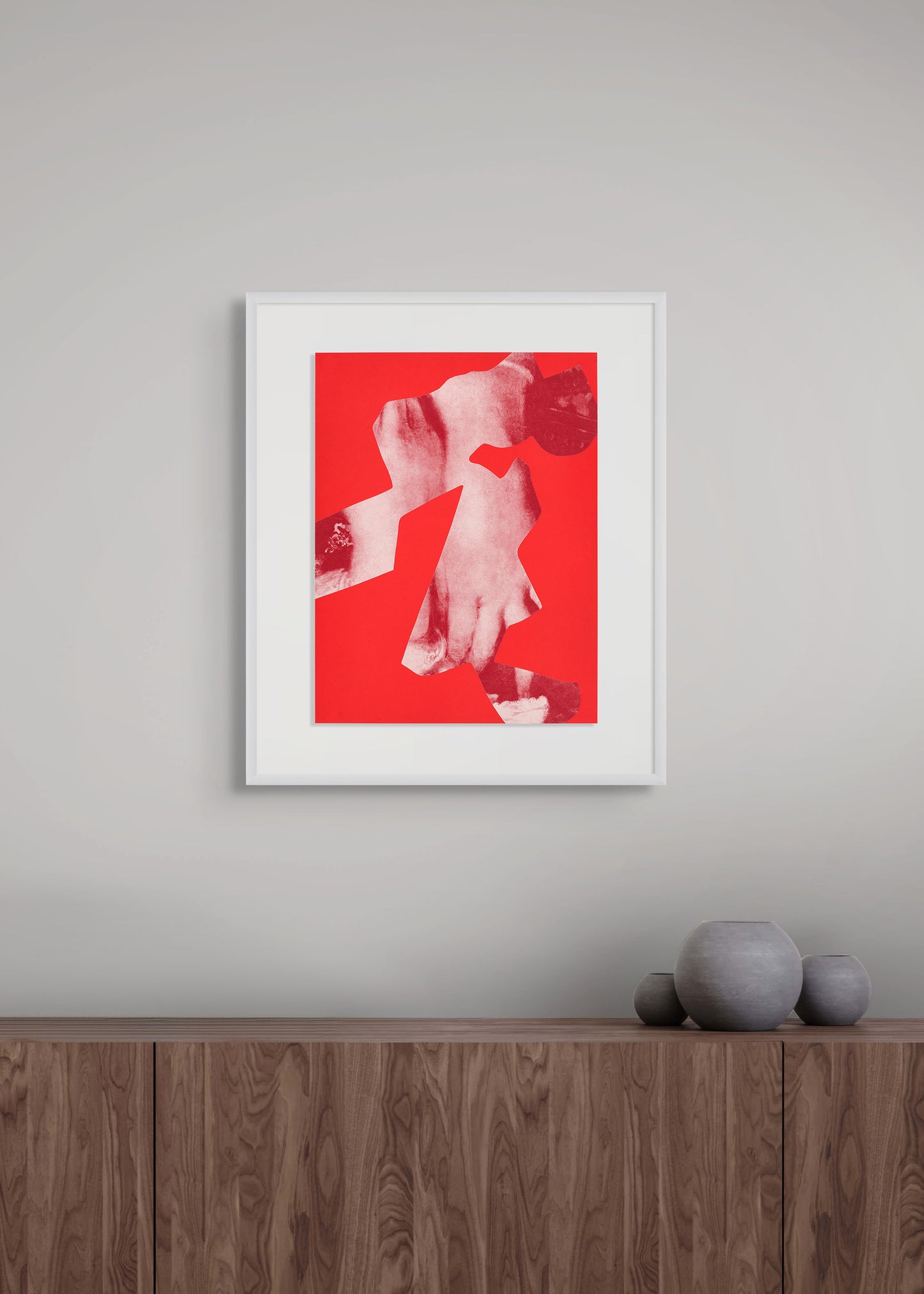 Framed artwork by Arturo Herrera with a red background and white abstract design on a gray wall above a wooden shelf.