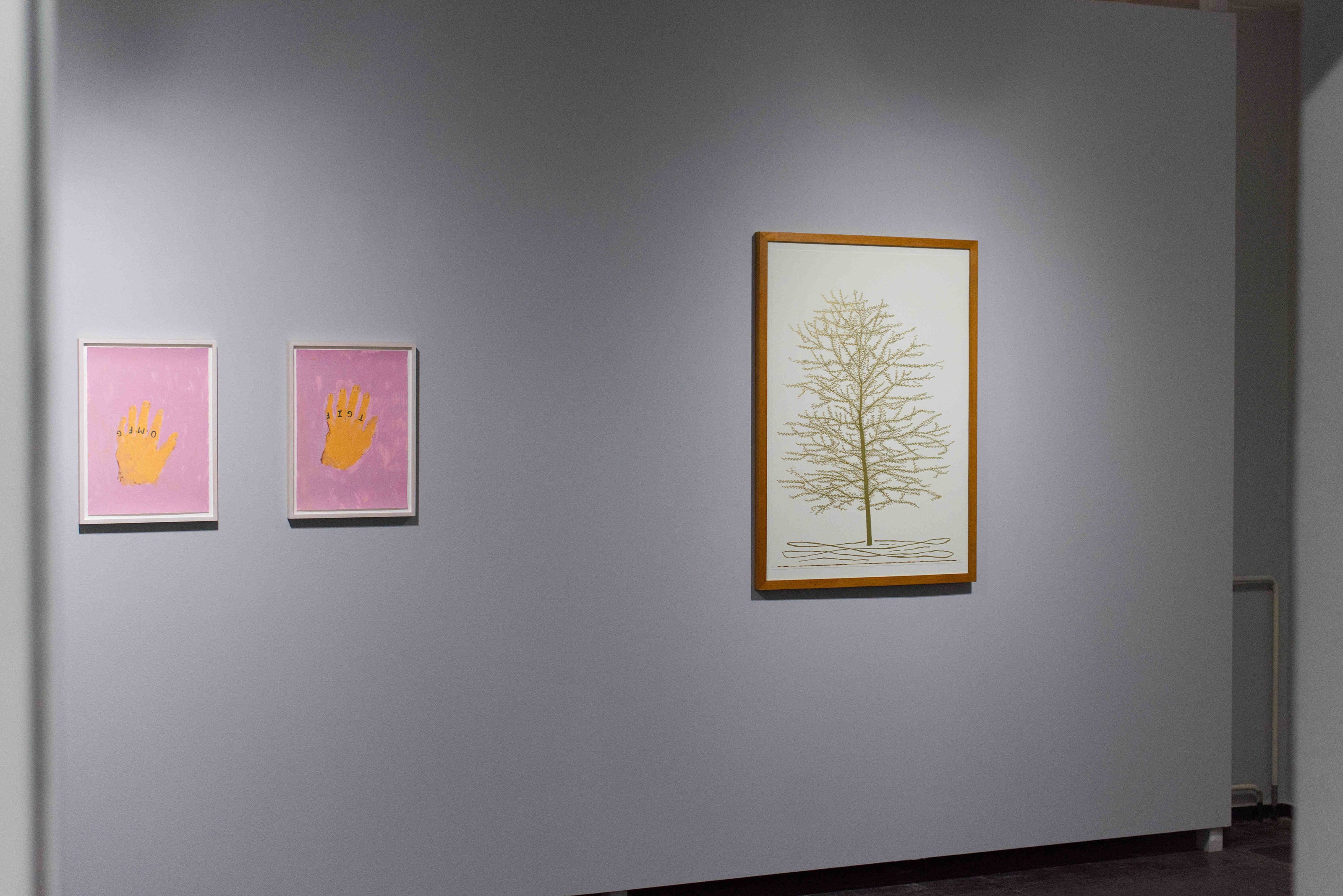 Artistic prints by Marlon Wobst and Stephen Chambers on a gray wall with a spotlight effect