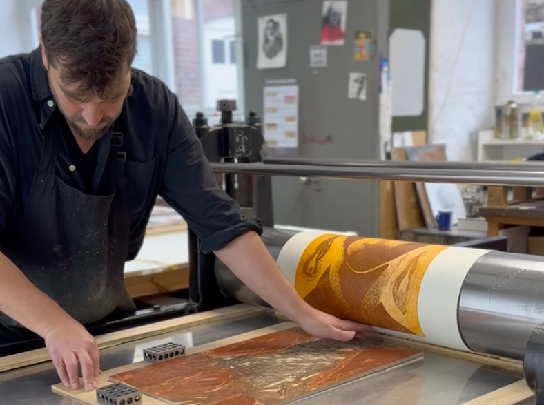 Man working with a printing press in a workshop setting